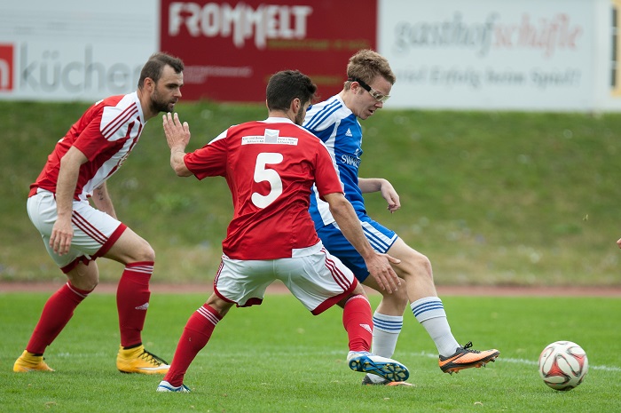Arpagaus (FC Trieen, blaues Jersey) mühlt sich hier gegen wie Spieler von US Schluein-Ilanz ab. Am Ende verlor Triesen 1:3.